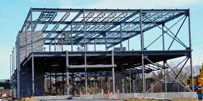 Two story commercial construction job site being built with steel beams and heavy machinery