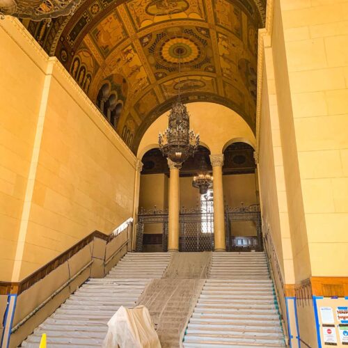 Yellow hallway with a mural on the ceiling being painted