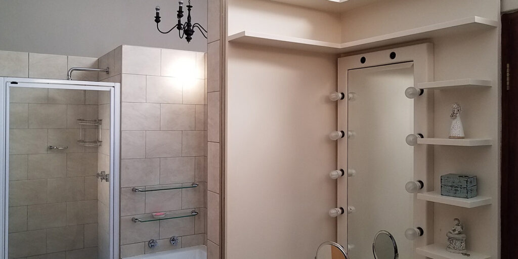 finished bathroom remodel from contractors, with a pink bathroom vanity and tiled shower